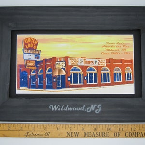 May include: A framed vintage postcard depicting Uncle Lou's Restaurant in Wildwood, New Jersey. The postcard shows the restaurant's exterior with a red brick facade, multiple windows, and a sign that reads "Uncle Lou's Restaurant". The text on the postcard reads "Uncle Lou's Atlantic and Pine Wildwood, NJ Circa 1960's - 70's".