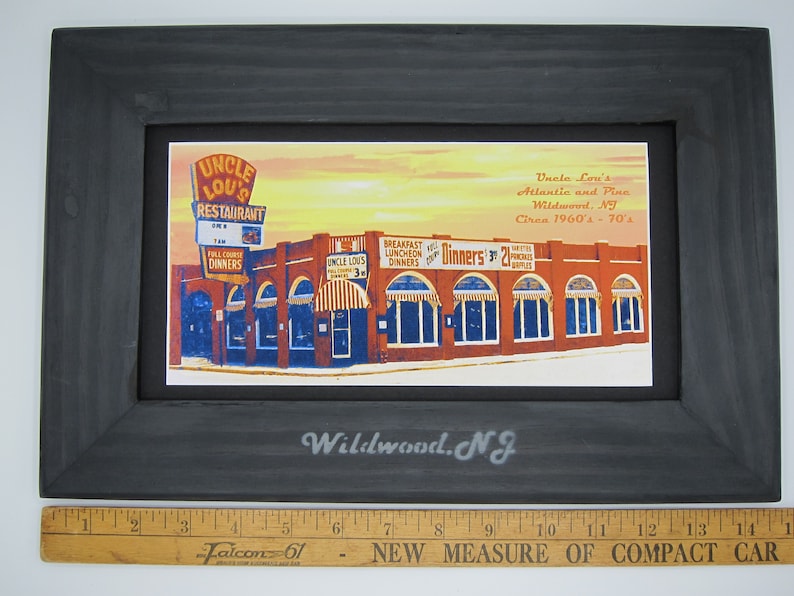 May include: A framed vintage postcard depicting Uncle Lou's Restaurant in Wildwood, New Jersey. The postcard shows the restaurant's exterior with a red brick facade, multiple windows, and a sign that reads "Uncle Lou's Restaurant". The text on the postcard reads "Uncle Lou's Atlantic and Pine Wildwood, NJ Circa 1960's - 70's".