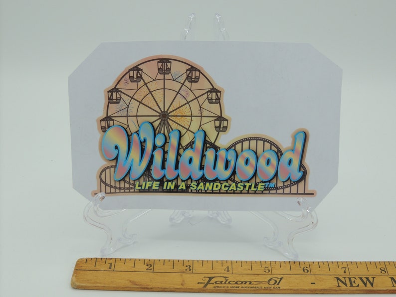 May include: A colourful sticker with the text "Wildwood Life in a Sandcastle" and a vintage illustration of a Ferris wheel.