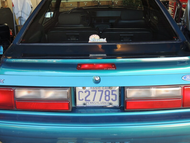 May include: Teal blue Ford Mustang with a Pennsylvania licence plate that reads "C27785 CLASSIC CAR". The car has a rear window sticker that reads "Wildwood".