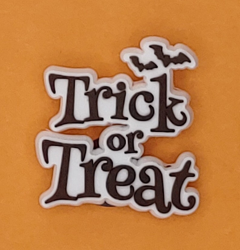 May include: White and black "Trick or Treat" Halloween shoe charm with two black bats above the text.