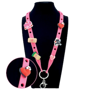 May include: Pink lanyard with multiple charms, including a heart, a bandage, and a pill bottle. The charms are attached to the lanyard, which has a key ring and a lobster clasp. The lanyard is displayed on a black mannequin.