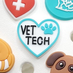 May include: A blue and white heart-shaped charm with the text "VET TECH" and a blue paw print.
