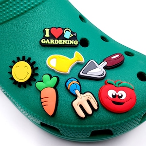 May include: A set of seven colorful garden-themed shoe charms. The charms include a sun, a watering can, a carrot, a fork, a trowel, a tomato, and a charm that says "I love gardening".