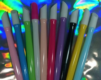 Puede incluir: Un juego de diez empujadores de cutículas para uñas con puntas de goma blanca. Los empujadores están hechos de plástico y vienen en una variedad de colores, incluyendo rosa, azul, verde, blanco y negro.