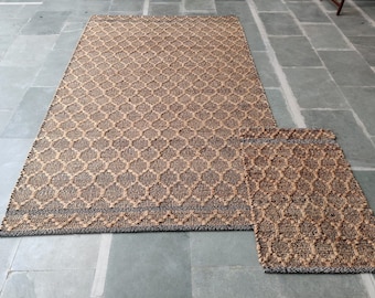 May include: Two brown and black patterned jute rugs. The larger rug is rectangular and the smaller rug is a runner.