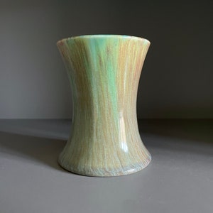 May include: A green and brown ceramic vase with a flared opening and a narrow base. The vase has a textured, wood-grain like finish.