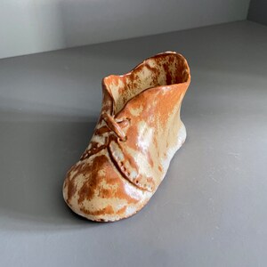 May include: A small ceramic shoe planter in brown and white with a lace detail.