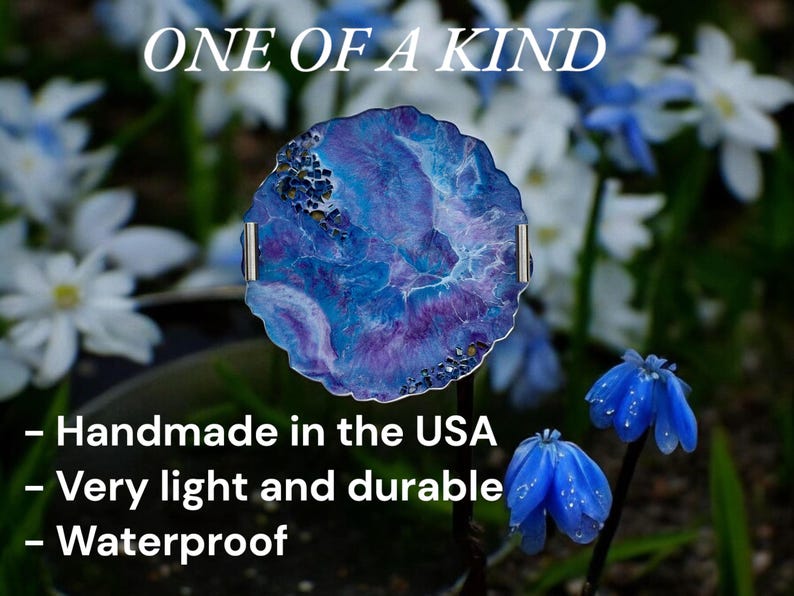May include: A round, blue and purple decorative piece with silver handles, set against a blurred floral background. The text "ONE OF A KIND" is at the top. The piece is handmade in the USA, very light and durable, and waterproof.