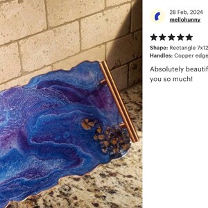May include: A rectangular resin tray, approximately 7 x 12 inches, with a vibrant blue and purple marbled design. It features copper-colored edges and handles. The tray has a decorative appearance.