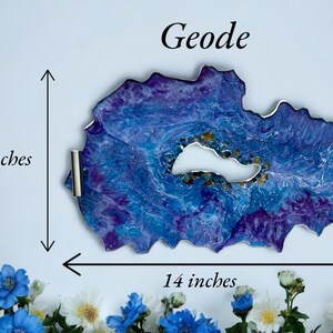 May include: A geode-shaped tray with a blue and purple marbled design, measuring 14 inches wide and 8 inches high. The tray has a white center and silver handles. The word "Geode" is written at the top.