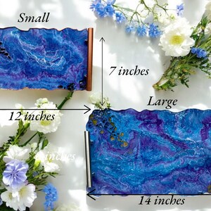 May include: Two decorative trays with a blue and purple marbled design. The small tray is 12 inches long and 7 inches wide. The large tray is 14 inches long and 7 inches wide. Both trays have copper or silver handles.