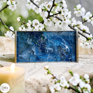 May include: A rectangular tray featuring a deep blue and white marbled resin surface with embedded dark blue glass fragments and metallic gold-toned side handles, set against a backdrop of white cherry blossom branches and a lit candle.