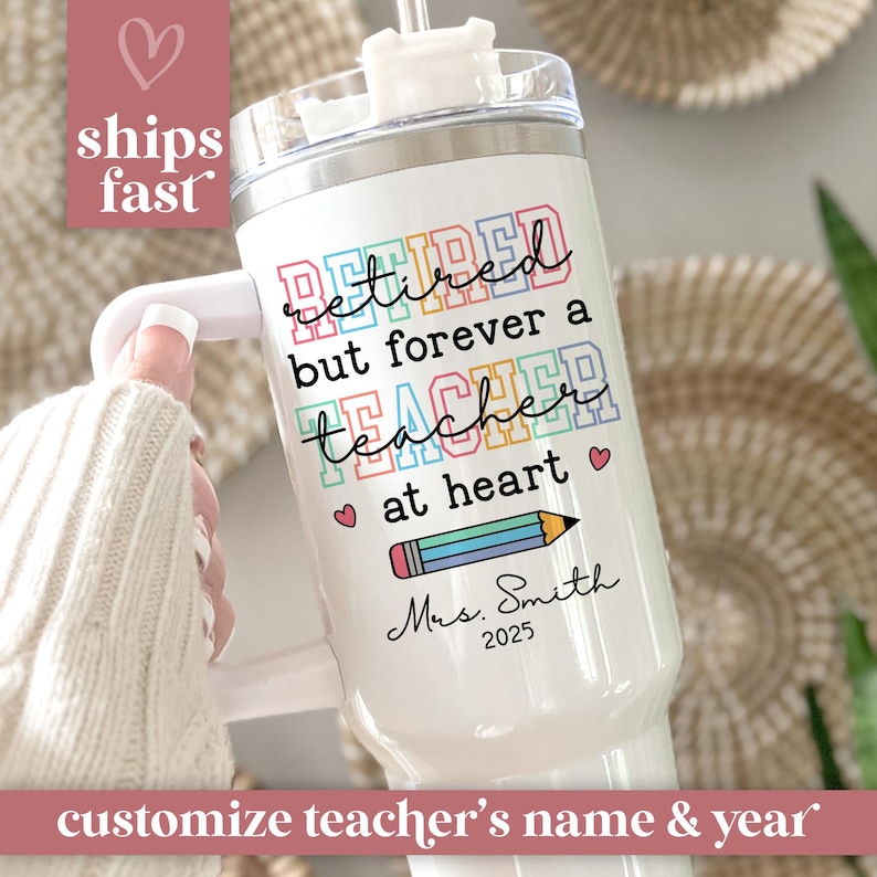May include: White insulated tumbler with a handle, featuring the text "Retired but forever a teacher at heart." Includes a pencil graphic and personalized name and year. The tumbler has a silver lid and a white handle.