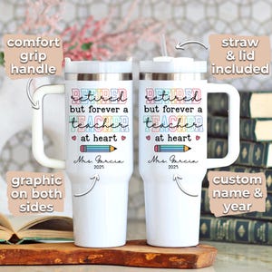 May include: Two white travel mugs with silver rims and large white handles. Each mug features the text "Retired but forever a teacher at heart" with a pencil graphic and the name "Mrs. Garcia 2025". One mug has a straw and lid.