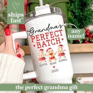 May include: White travel mug with a handle, featuring the text "Grandma's PERFECT BATCH" in black and red. It includes gingerbread people illustrations and the names Olivia, Noah, and Sophia. The mug also has the year 2025.