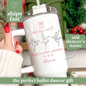 May include: White travel mug with a handle, featuring a ballet dancer design and the text "Sorry, can't. Nutcracker season." The mug includes the option to add a dancer's name. The text "ships fast" is also visible.