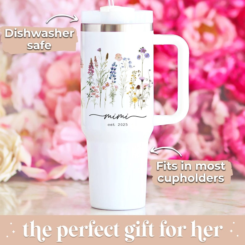 May include: White tumbler with a handle, featuring a floral design and the text "mimi est. 2025". The tumbler is labeled "Dishwasher safe" and "Fits in most cupholders".