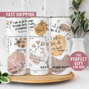 May include: Three white tumblers with inspirational quotes and floral designs. The quotes are from the Bible and include "I can do all things through Christ who strengthens me", "The Lord will fight for me", and "I trust in the Lord with all my heart".