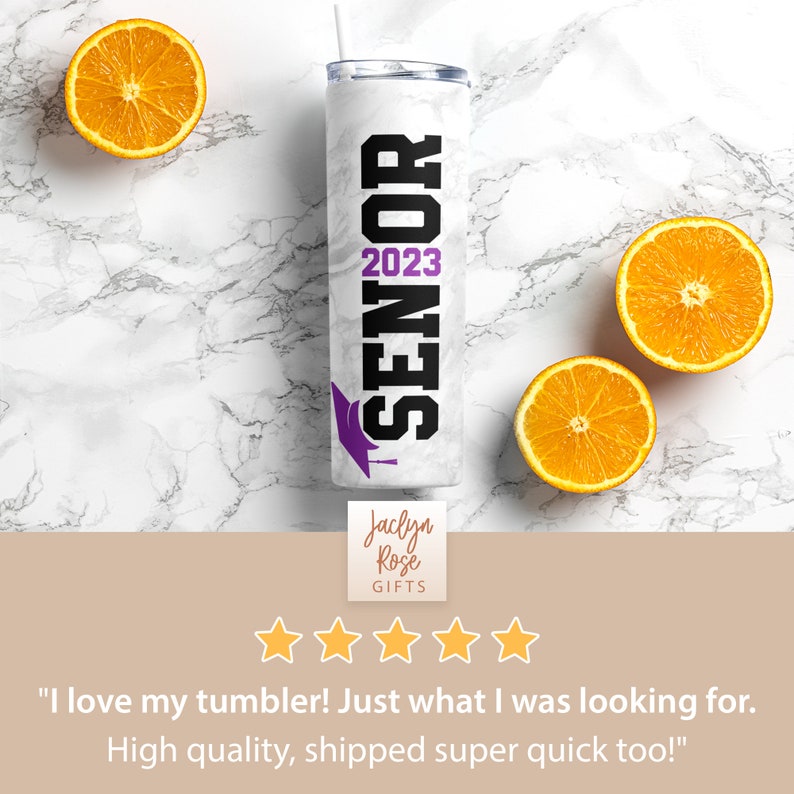 May include: White tumbler with a black and purple design that says "SENIOR 2023".