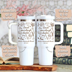 K&ouml;nnte beinhalten: Zwei wei&szlig;e isolierte Becher mit Komfortgriff, Strohhalm und Deckel. Jeder Becher hat eine Grafik mit dem Text "Local sourdough dealer" und "Mia's Homemade Bread Est 2025". Das Design ist auf beiden Seiten, mit der Option, einen Namen und ein Jahr hinzuzuf&uuml;gen.