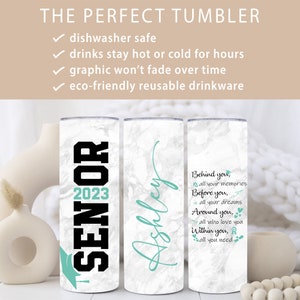 May include: Three stainless steel tumblers with white marble print. The first tumbler has the text "Senior 2023" in black with a teal graduation cap. The second tumbler has the name "Ashley" in teal script. The third tumbler has the text "Behind you, all your memories. Before you, all your dreams. Around you, all who love you. Within you, all you need." in teal with a teal graduation cap, airplane, heart, and ribbon.