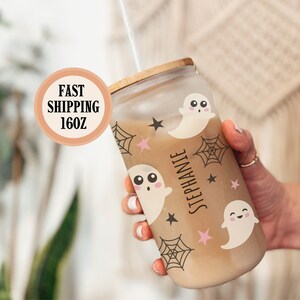 May include: A clear glass tumbler with a bamboo lid, filled with a beverage and a straw. The tumbler is decorated with cute ghost and spiderweb graphics. The name "Stephanie" is printed vertically on the side. The tumbler holds 16 ounces.