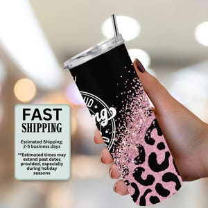 May include: A black and pink tumbler with a lid and straw. The tumbler has a leopard print design and the words "Good Vibes Only" in white. The tumbler is held in a hand.