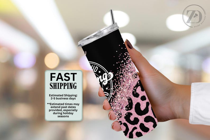 May include: A black and pink tumbler with a lid and straw. The tumbler has a leopard print design and the words "Good Vibes Only" in white. The tumbler is held in a hand.