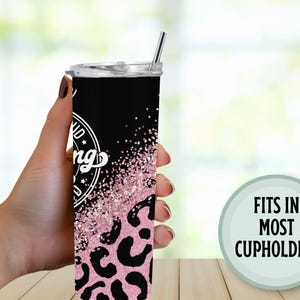 May include: A black and pink tumbler with a leopard print design and the words "Kind of a big deal" in a white circle. The tumbler has a silver straw and the text "Fits in most cupholders" in a green circle.