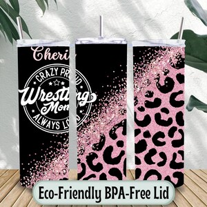 May include: Three stainless steel tumblers with lids and straws. The tumblers have a black background with pink glitter and leopard print designs. One tumbler has the text "Cheri Crazy Proud Wrestling Mom Always Loved".