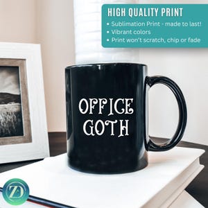 May include: Black ceramic mug with the words "OFFICE GOTH" in white, stylized font. The mug has a curved handle and sits on a stack of white books. The image also includes a framed picture and text that reads "HIGH QUALITY PRINT".