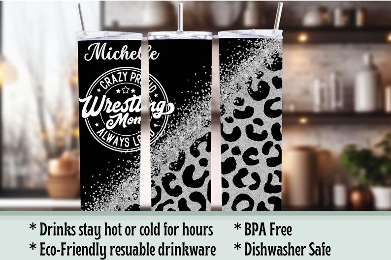 May include: A black and silver tumbler with a lid and straw. The tumbler features the name "Michelle" and the text "Crazy Proud Wrestling Mom Always Loves" in white. The right side has a silver leopard print.