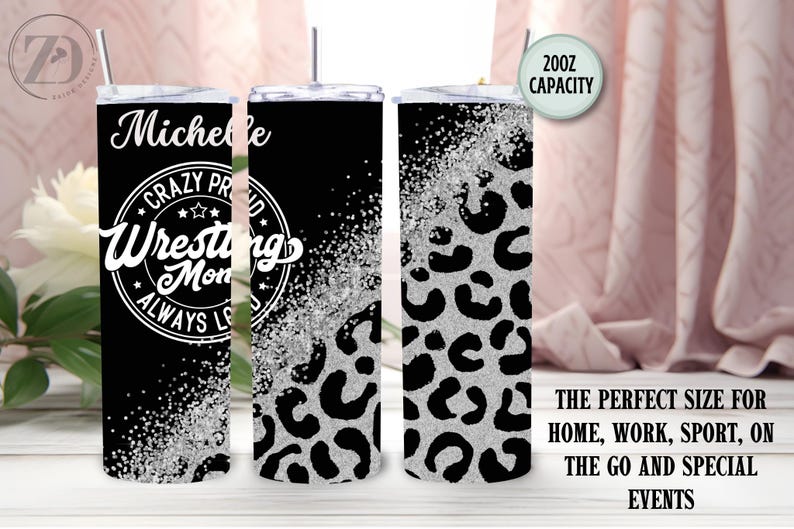 May include: A black and silver tumbler with a lid and straw. The tumbler features the text "Michelle Crazy Proud Wrestling Mom Always Loves" in white. The design includes a leopard print pattern and a 591ml capacity.