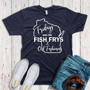 Op de afbeelding: Een marineblauw t-shirt met een witte omtrek van de staat Wisconsin. De tekst "Fridays are for Fish Frys & Old Fashioneds" staat op het shirt gedrukt.