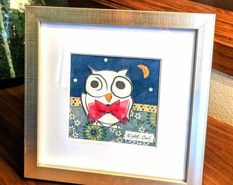 May include: A framed paper craft artwork featuring a white owl with a red bow tie against a blue background with stars and a crescent moon. The text "Night Owl!" is written below the owl.