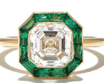 Könnte beinhalten: Ein goldener Ring mit einem quadratischen Diamanten, der von einem Heiligenschein aus smaragdgrünen Steinen umgeben ist.