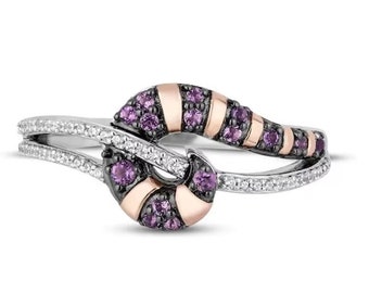 Puede incluir: Un anillo de plata y oro rosa con un diseño de espiral morado y negro. El anillo está engastado con pequeños diamantes y piedras preciosas moradas.