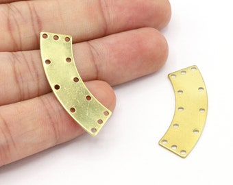 May include: Two gold metal curved shapes with holes around the edges. The shapes are on a white surface.