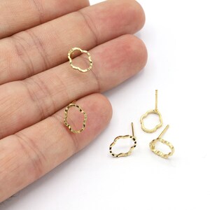 May include: Four gold-toned earring settings with a scalloped edge in the shape of a cloud. The settings have a post on the back for attaching earrings.