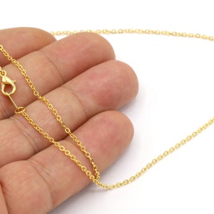 May include: A gold chain necklace with a lobster clasp closure. The chain is delicate and has a fine, round link design.