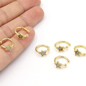 May include: Five gold-toned ear cuffs with a star-shaped design. Each star is adorned with colorful rhinestones.