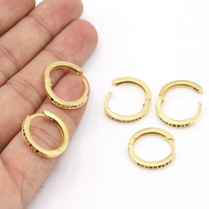May include: Four gold hoop earrings with a single row of colorful gemstones around the edge.