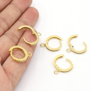May include: Five gold-toned hoop earring findings with a clear crystal accent. The findings have a hinged closure and a small loop for attaching a charm or pendant.