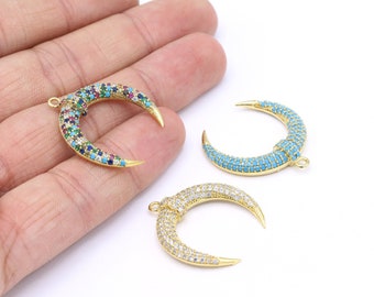 Puede incluir: Tres dijes de media luna dorados con piedras de colores diferentes. Los dijes están engastados con pequeñas piedras de colores y tienen una punta puntiaguda.