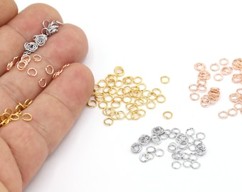 May include: Assortment of small jump rings in gold, rose gold, and silver colors. The jump rings are ideal for jewelry making and crafting.