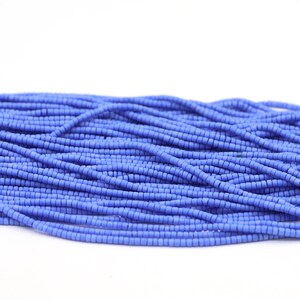 May include: A close-up of a pile of small, light blue glass beads. The beads are round and have a matte finish.