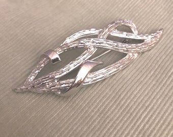 Broche abstracto calado en tono plateado, firmado por Coro, de estilo vintage.