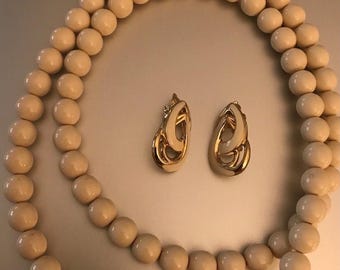 Conjunto de joyería vintage con collar de cuentas Trifari y pendientes con clip esmaltados en tono dorado.