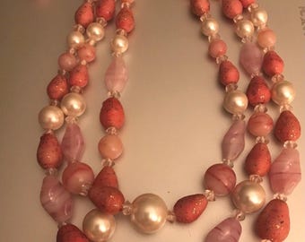 Collar vintage de tres hilos con cuentas multiforma en cristal artístico rosa coral y tono dorado, firmado por Japón.